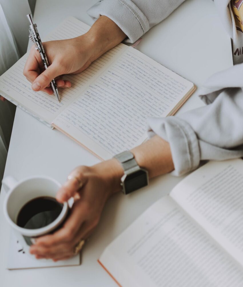 Photo by lil artsy on <a href="https://www.pexels.com/photo/person-writing-on-notebook-while-holding-coffee-mug-3278757/" rel="nofollow">Pexels.com</a>